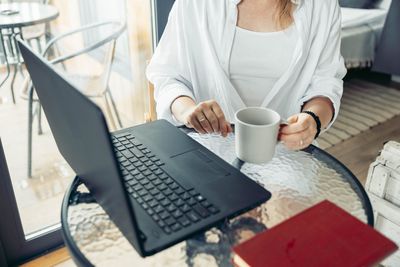 Midsection of woman using laptop on table