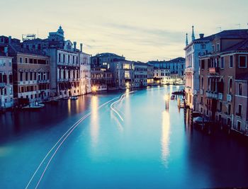 Light trails in canal amidst buildings