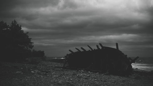 Abandoned boat on field against sky