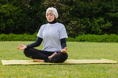 Attractive woman in hijab training in park, meditating. 