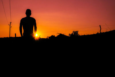 Silhouette man standing at sunset