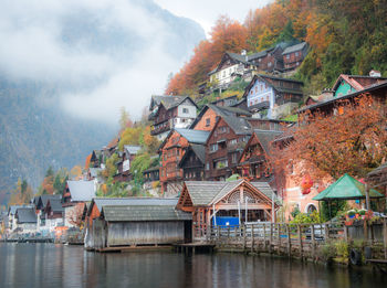 Houses by lake and buildings against sky