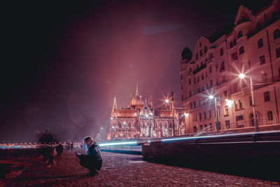 People walking on illuminated city at night