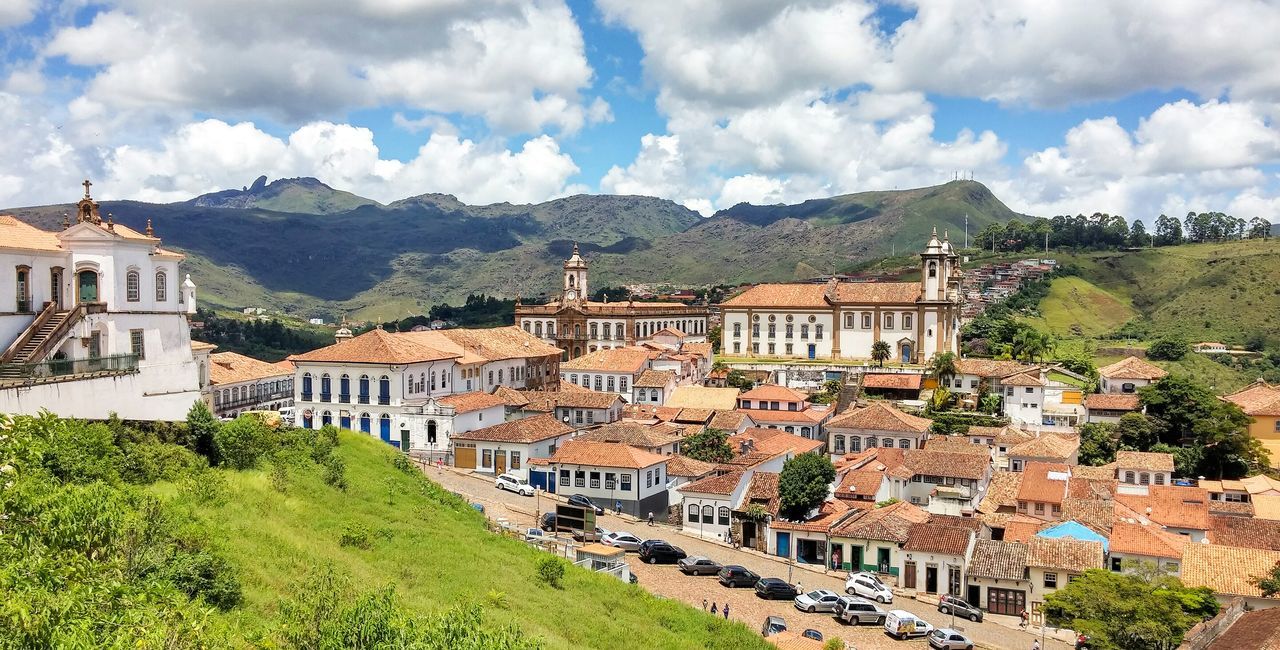 architecture, building exterior, built structure, mountain, sky, house, cloud - sky, residential structure, cloud, town, mountain range, residential building, cloudy, day, tree, village, outdoors, old, no people, hill