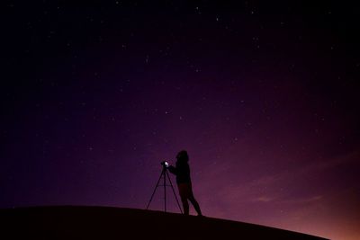 Silhouette person photographing against sky at night