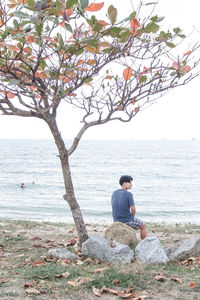 Men sitting on beach against clear sky