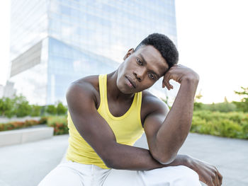 Young man wearing yellow vest in front of modern building