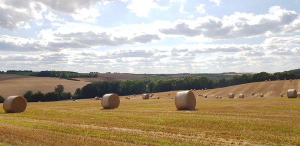 Hay bales on field against sky