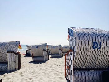 Hooded chairs on beach against clear sky