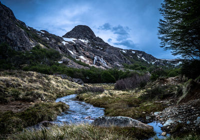 Scenic view of river by mountains against sky