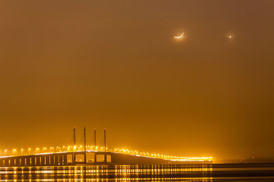 Illuminated bridge against sky at night