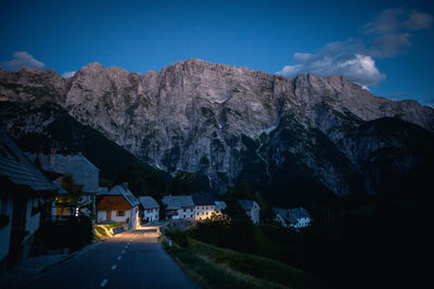 Road and houses by rocky mountains at dusk