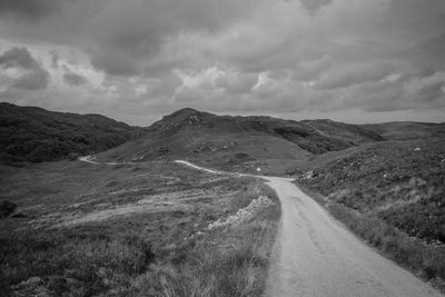 Road leading towards mountains against sky