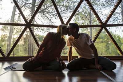 Rear view of couple sitting on window