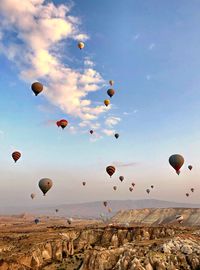 Hot air balloons flying over landscape against sky