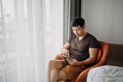 Young woman using mobile phone while sitting at home