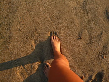 Low section of person standing on sand at beach