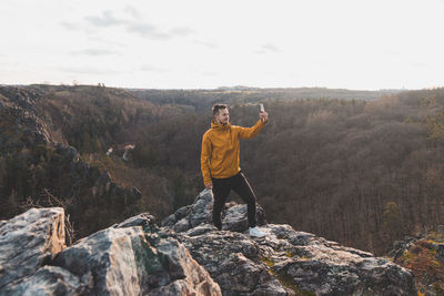 Rear view of man standing on rock against mountain