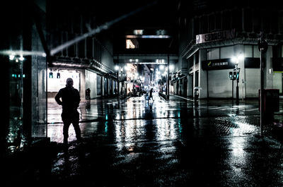 People walking on wet road at night