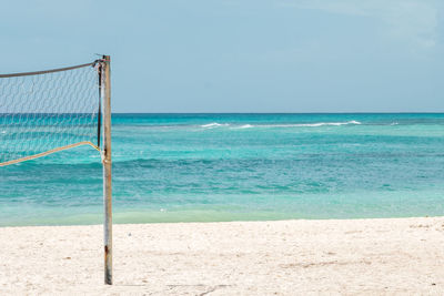 Volleyball net at beach against sky
