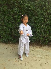 Full length of cute girl in karate uniform standing outdoors