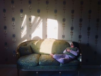 Full length of girl relaxing on sofa at home