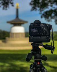 Close-up of camera in front of a monument on field against sky