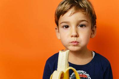 Close-up portrait of cute boy holding orange