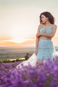 A beautiful young girl against the sunset and a beautiful sky in a lavender field. 