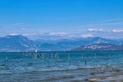 Scenic view of sea and mountains against blue sky