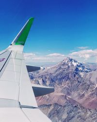 Aerial view of snowcapped mountains against blue sky