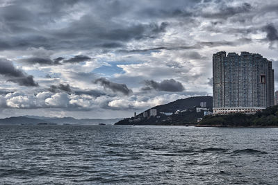 Sea by city buildings against sky