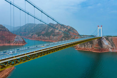 Bridge over mountain against sky