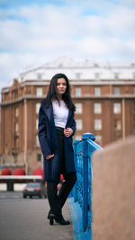 Portrait of young woman standing against wall