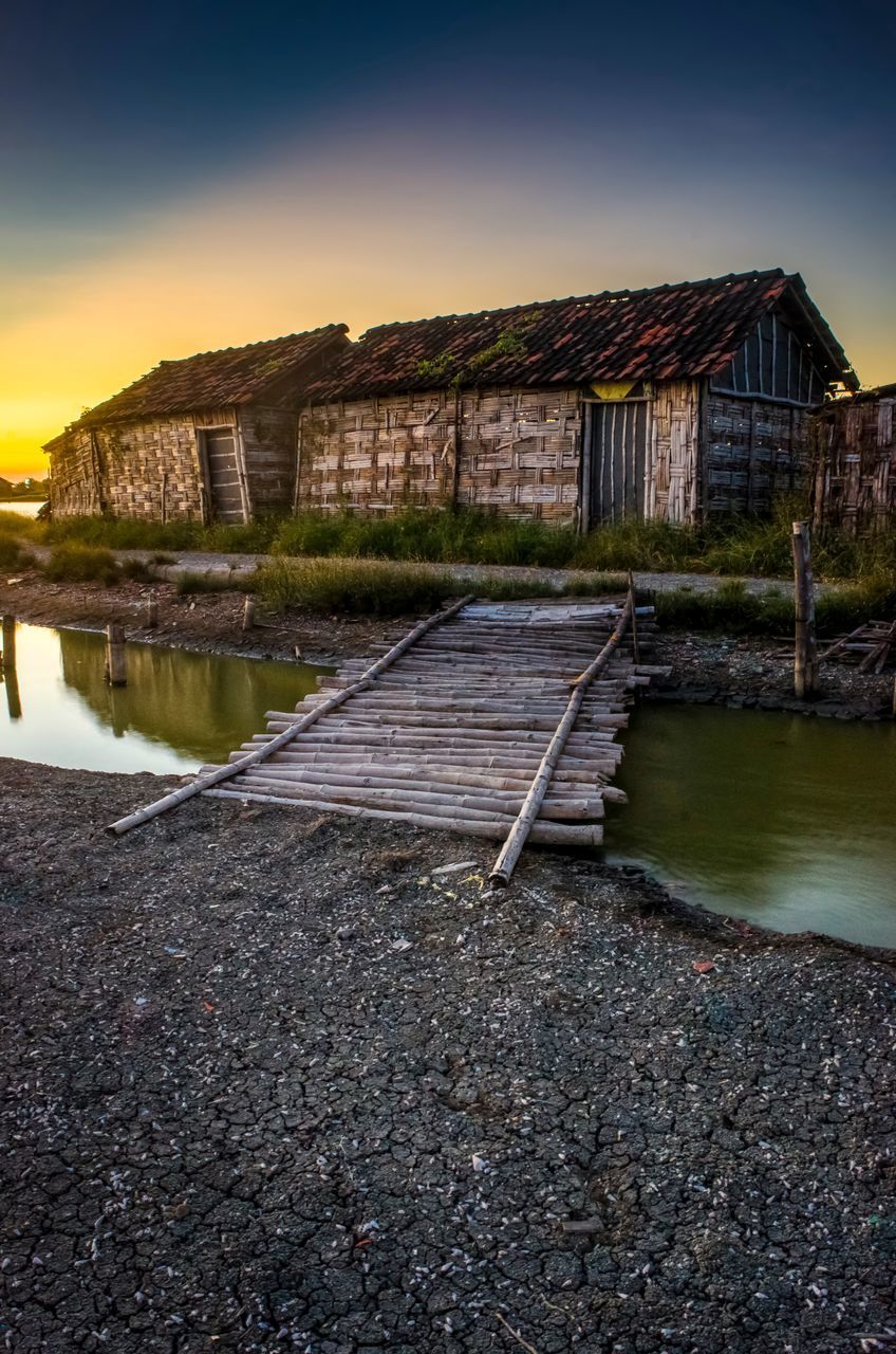 OLD HOUSE BY LAKE AGAINST BUILDINGS