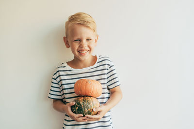 Portrait of smiling boy holding ice cream against white background