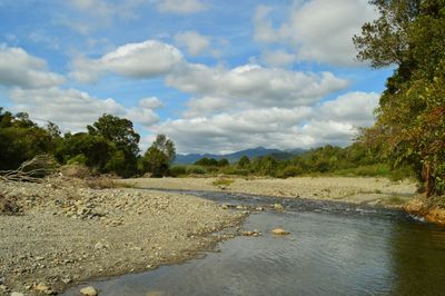 Scenic view of river against cloudy sky