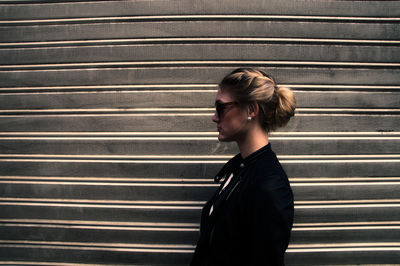 Side view of woman wearing sunglasses against wall