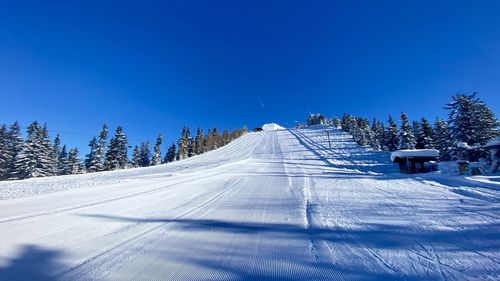 Snow covered landscape against clear blue sky