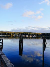 Wooden post in lake against sky