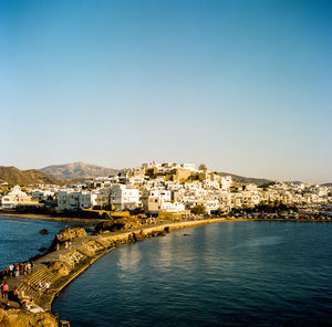 Townscape by sea against clear blue sky