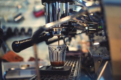 Close-up of espresso maker pouring coffee in cup at cafe