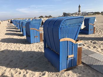 Hooded chairs on beach against blue sky