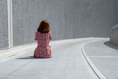 Sad lonely woman sitting on footpath