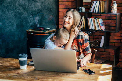 Mom and son laugh and hug, mom working from home. the concept of learning and parenthood. 