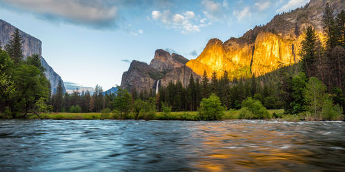 Scenic view of river by mountains against sky