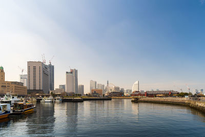 City buildings by river against sky