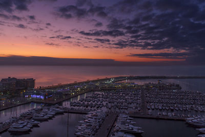 High angle view of city by sea against sky during sunset