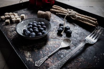 High angle view of blueberries with spoon and fork on tray