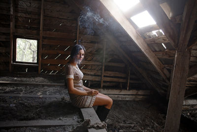 Full length of woman sitting in abandoned room